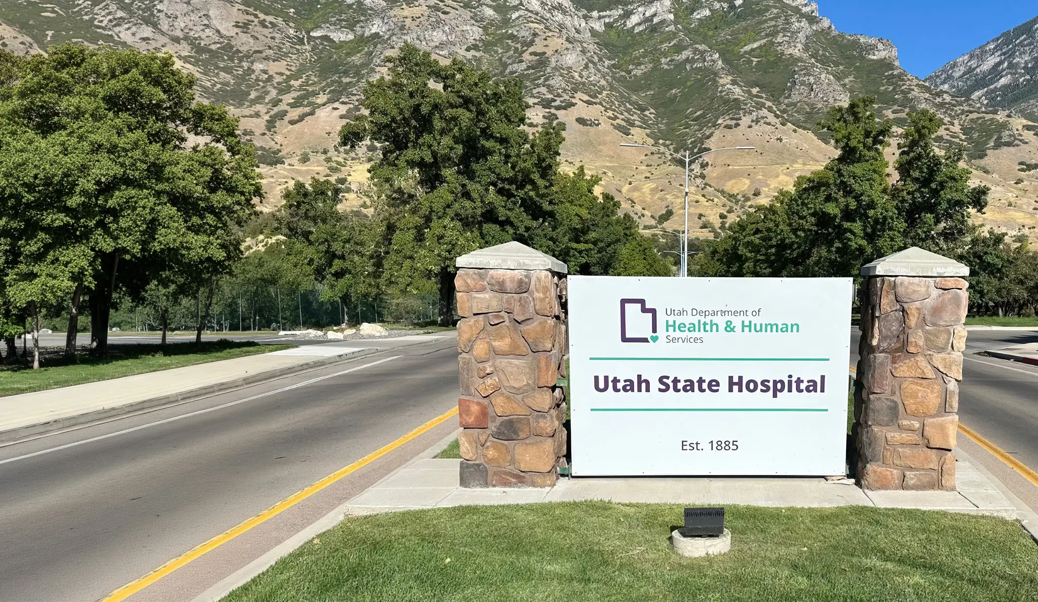Entrance sign for the Utah State Hospital, Utah Department of Health and Human Services, established 1885, with mountains behind